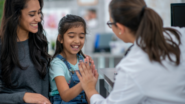 a child high fiving a doctor next to a woman