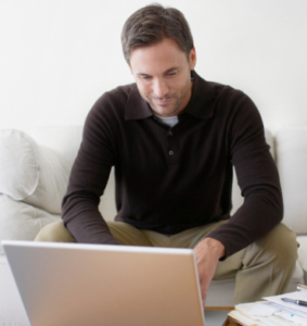 a man sitting on a couch looking at a laptop