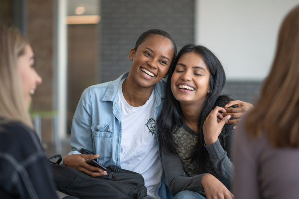 a woman smiling with her eyes closed and her arms around another woman