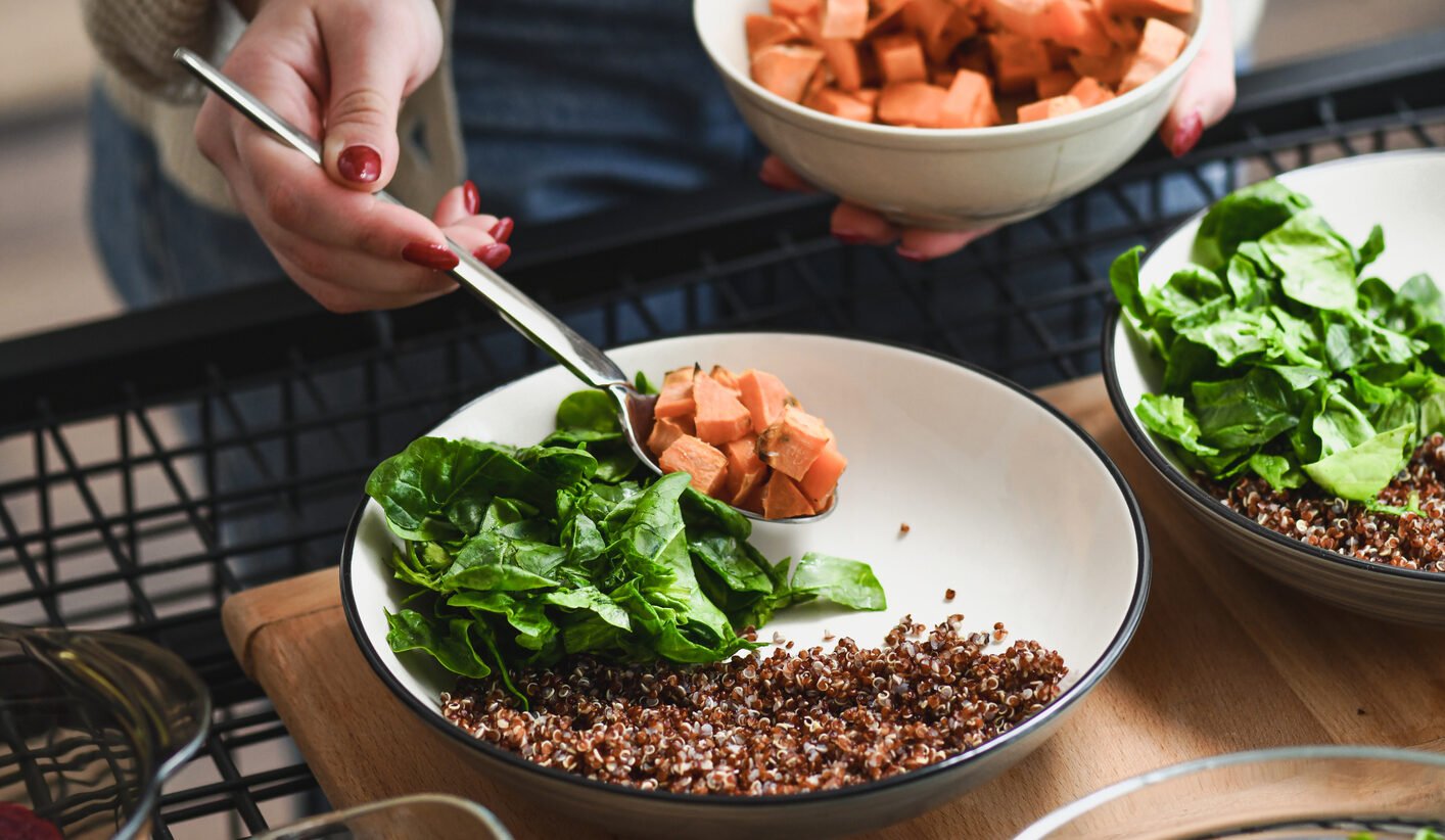Woman assembling a bowl of grains and vegetables