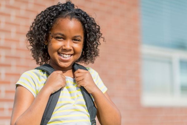 a smiling kid wearing a backpack
