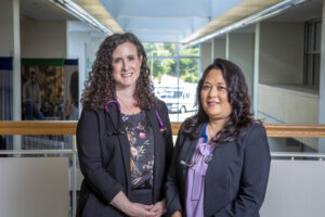 Two women in professional attire smiling.