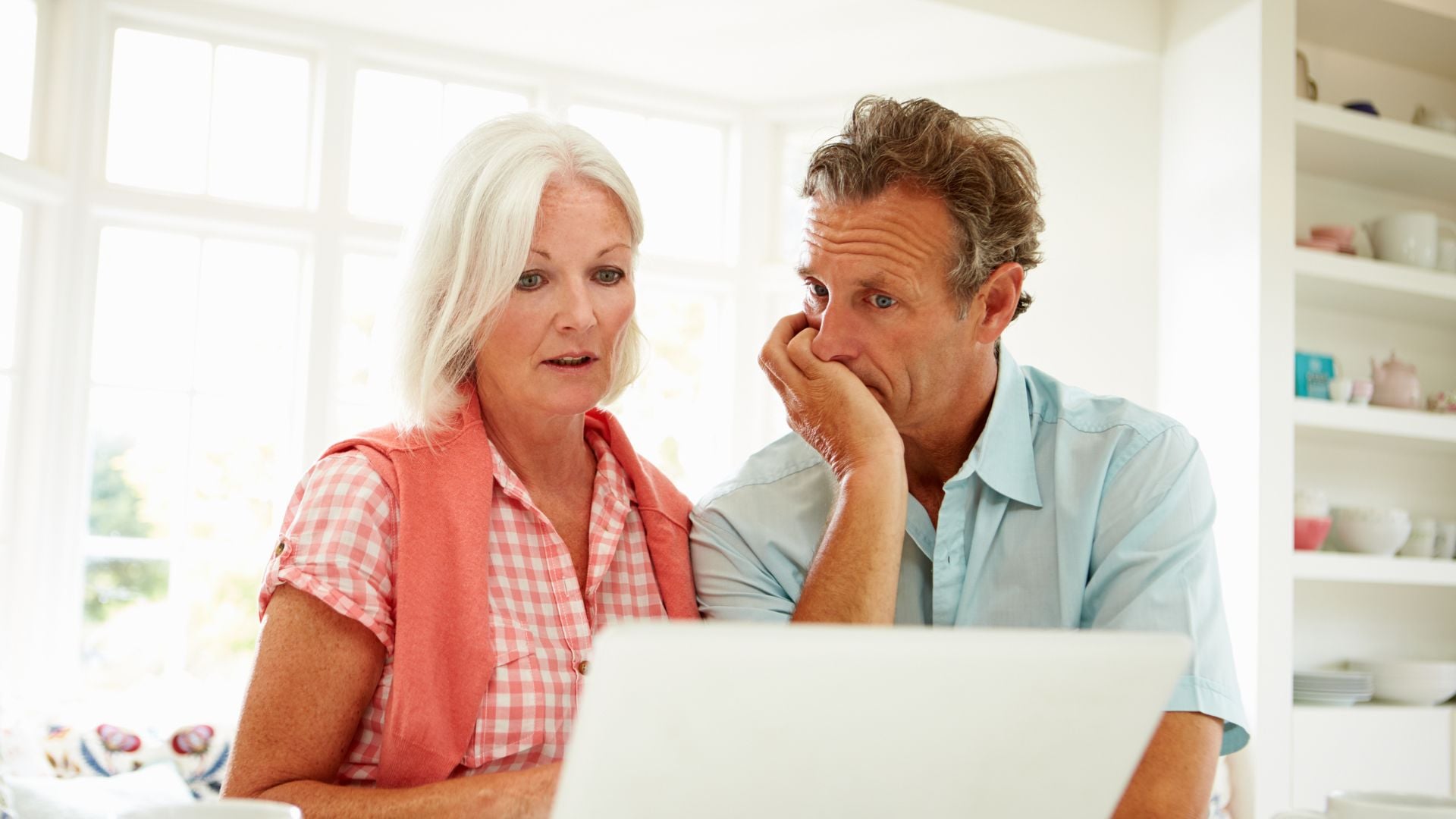 middle aged couple staring at the computer and discussing